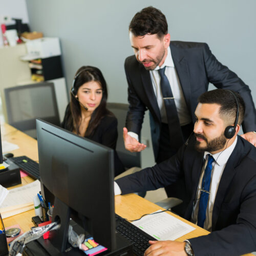 Male supervisor training a latin executive at a call center. Manager explaining work stuff to the employees offering tech support and customer service
