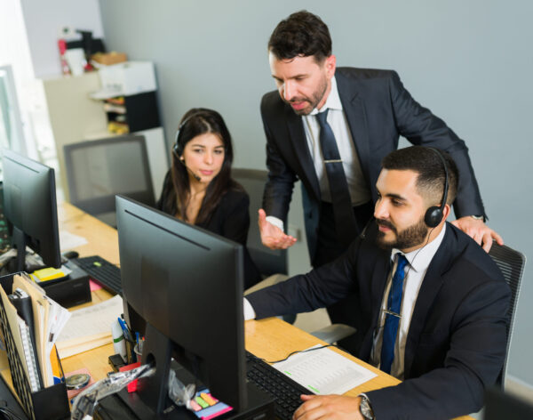 Male supervisor training a latin executive at a call center. Manager explaining work stuff to the employees offering tech support and customer service