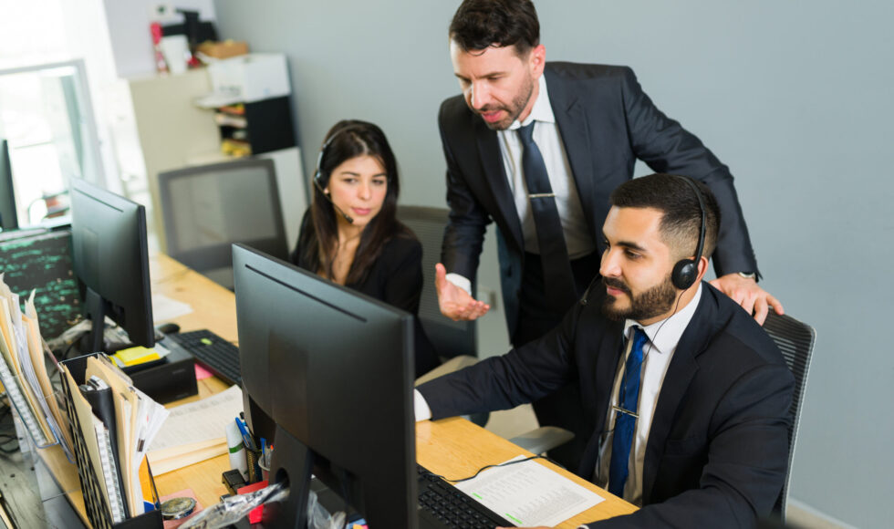 Male supervisor training a latin executive at a call center. Manager explaining work stuff to the employees offering tech support and customer service