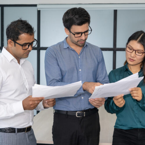 Multiethnic business team analyzing financial reports. Smart experts presenting papers to group leader. Teamwork and analysis concept