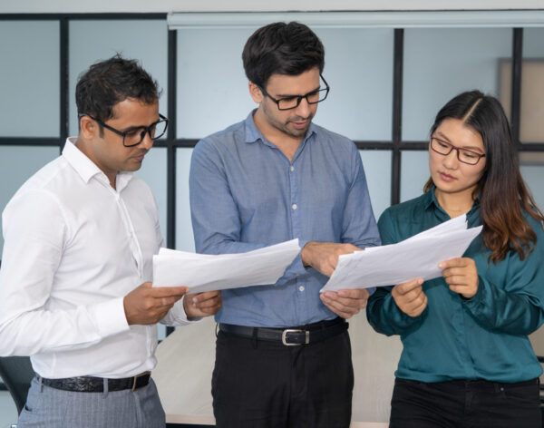 Multiethnic business team analyzing financial reports. Smart experts presenting papers to group leader. Teamwork and analysis concept