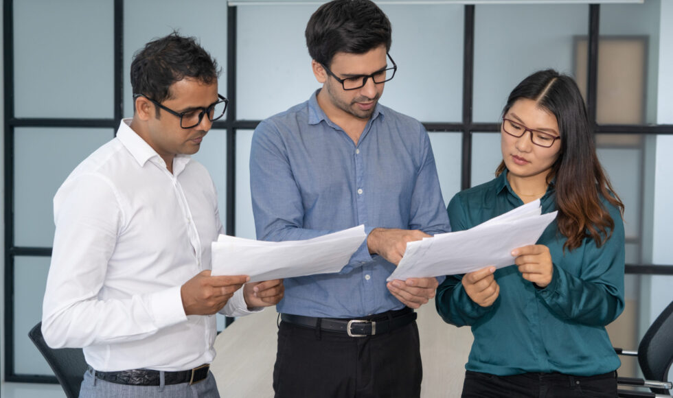Multiethnic business team analyzing financial reports. Smart experts presenting papers to group leader. Teamwork and analysis concept